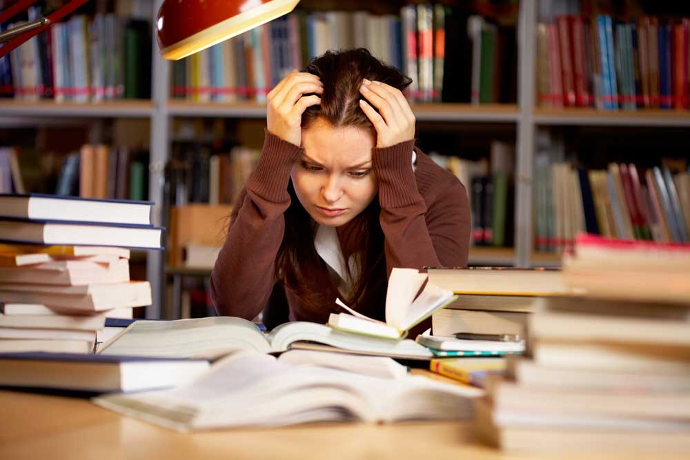 woman with head in her hands looking sad as she studies